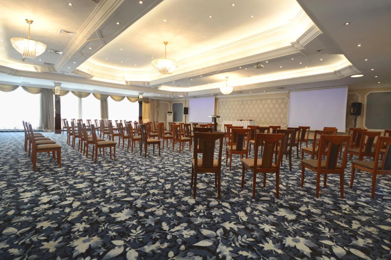 Akgun Istanbul Hotel Exterior foto The photo shows a spacious room set up for an event or presentation. There are several rows of wooden chairs arranged in a semi-circle or open format, facing a blank wall that is likely meant for a screen or presentation. The floor is covered with pa