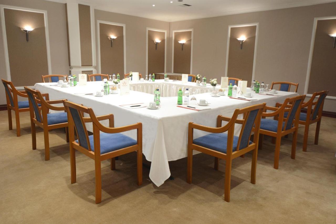 Akgun Istanbul Hotel Exterior foto The image shows a conference or meeting room setup. There is a large rectangular table covered with a white tablecloth. Surrounding the table are wooden chairs, each with blue cushions. On the table, there are several bottles of water and small plate
