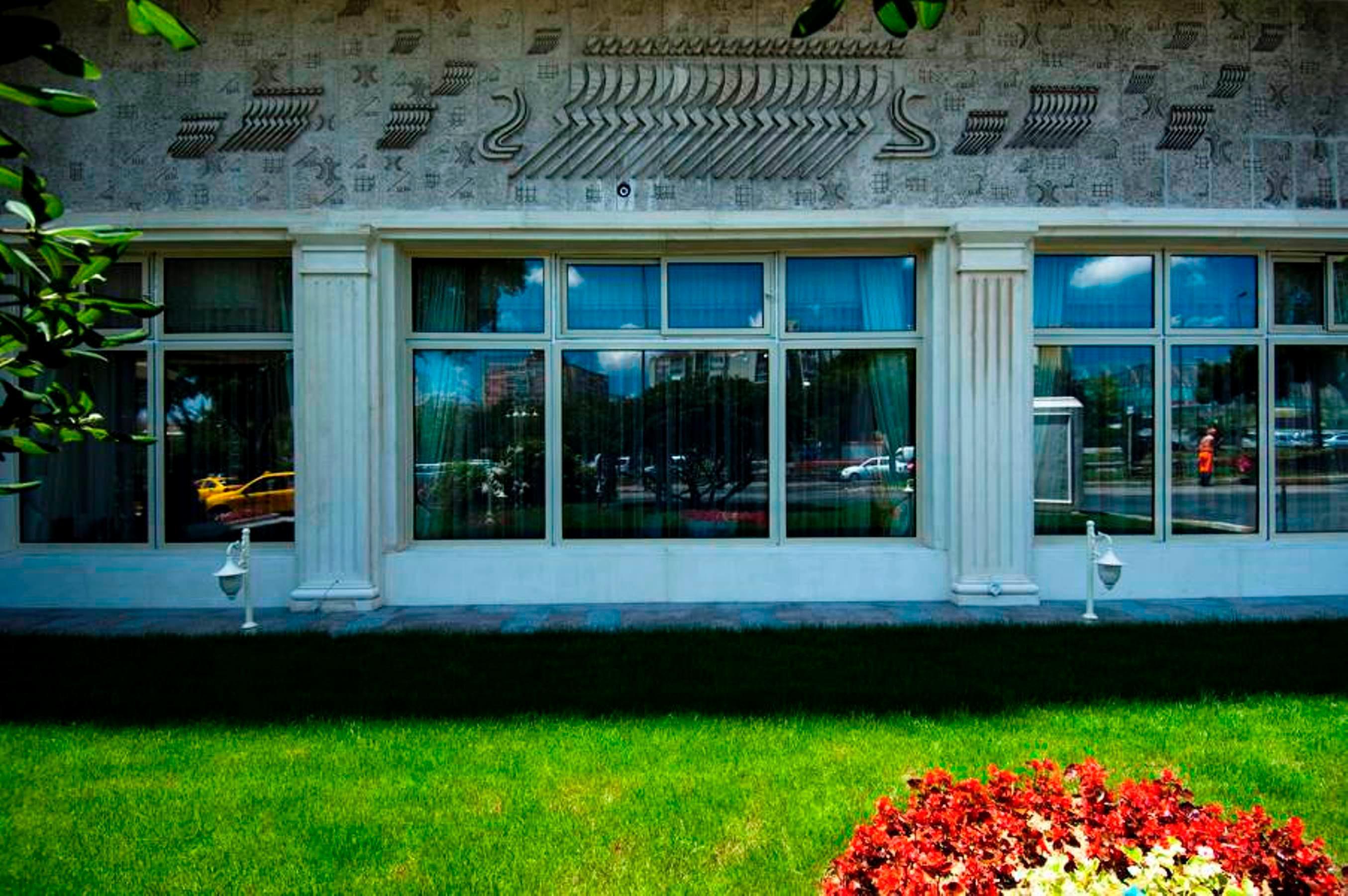 Akgun Istanbul Hotel Exterior foto The photo shows the exterior of a building with a decorative wall featuring intricate patterns. The façade is marked by several large windows that are framed with columns, giving it a classic architectural style. In front of the building, there is a 