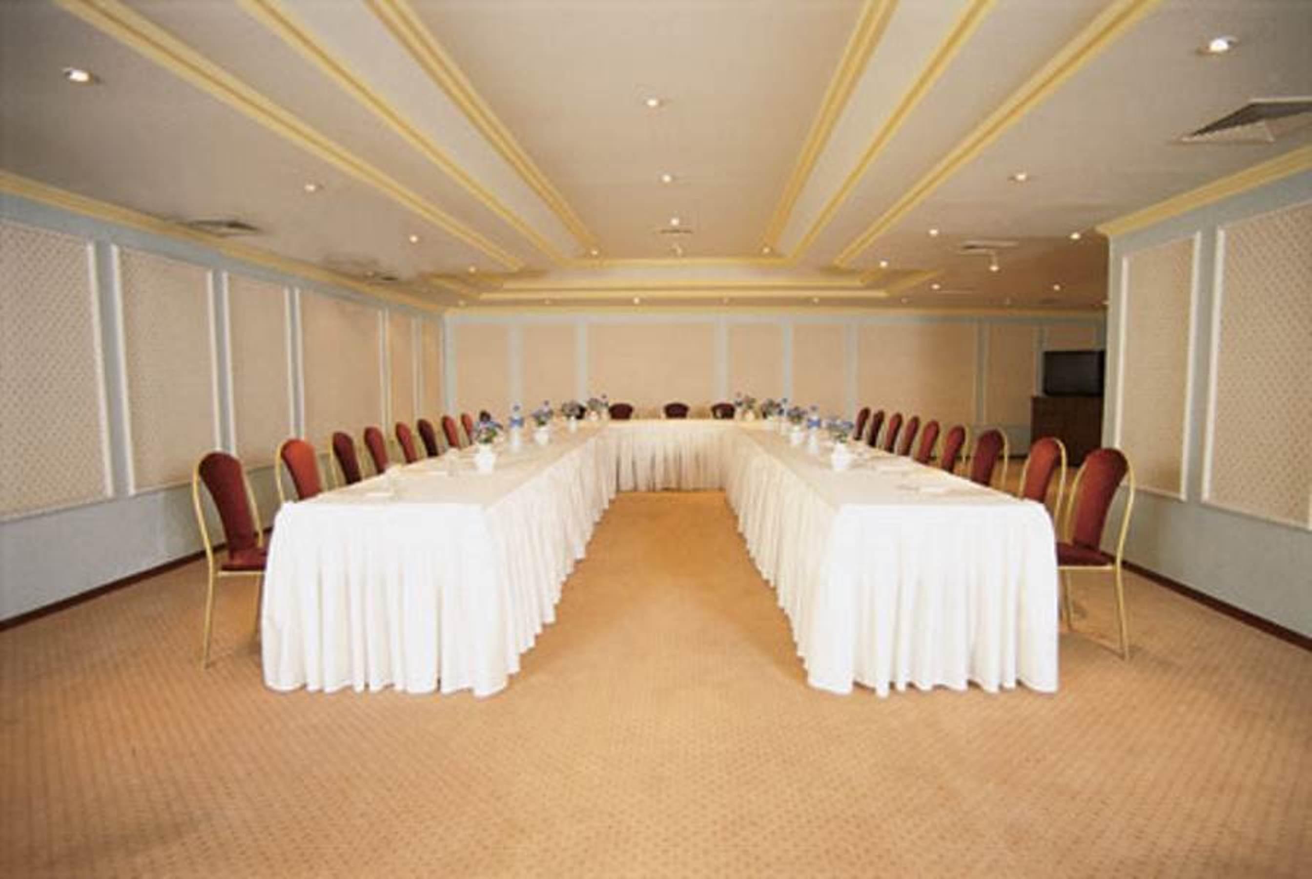 Akgun Istanbul Hotel Exterior foto The photo shows a conference room set up for a meeting. There are two long tables arranged in a U-shape, covered with white tablecloths. Each table has chairs lined along the sides, all with red upholstery. The room has a well-lit ambiance, with a ce
