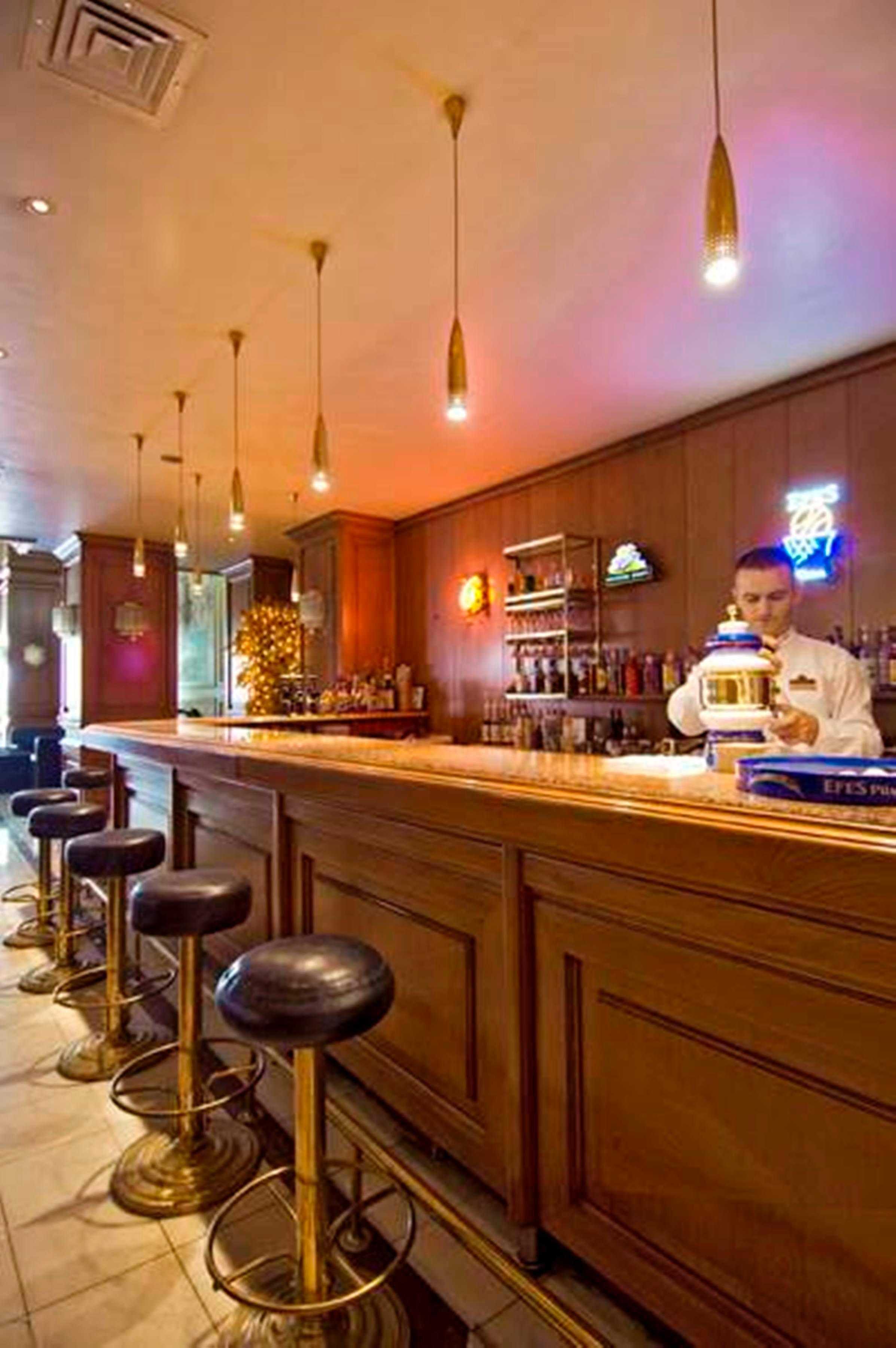 Akgun Istanbul Hotel Exterior foto The photo shows a bar area with a polished wooden counter. There are several bar stools positioned along the counter. Behind the bar, shelves are stocked with various bottles of alcoholic beverages, and there are neon signs adding a colorful ambiance