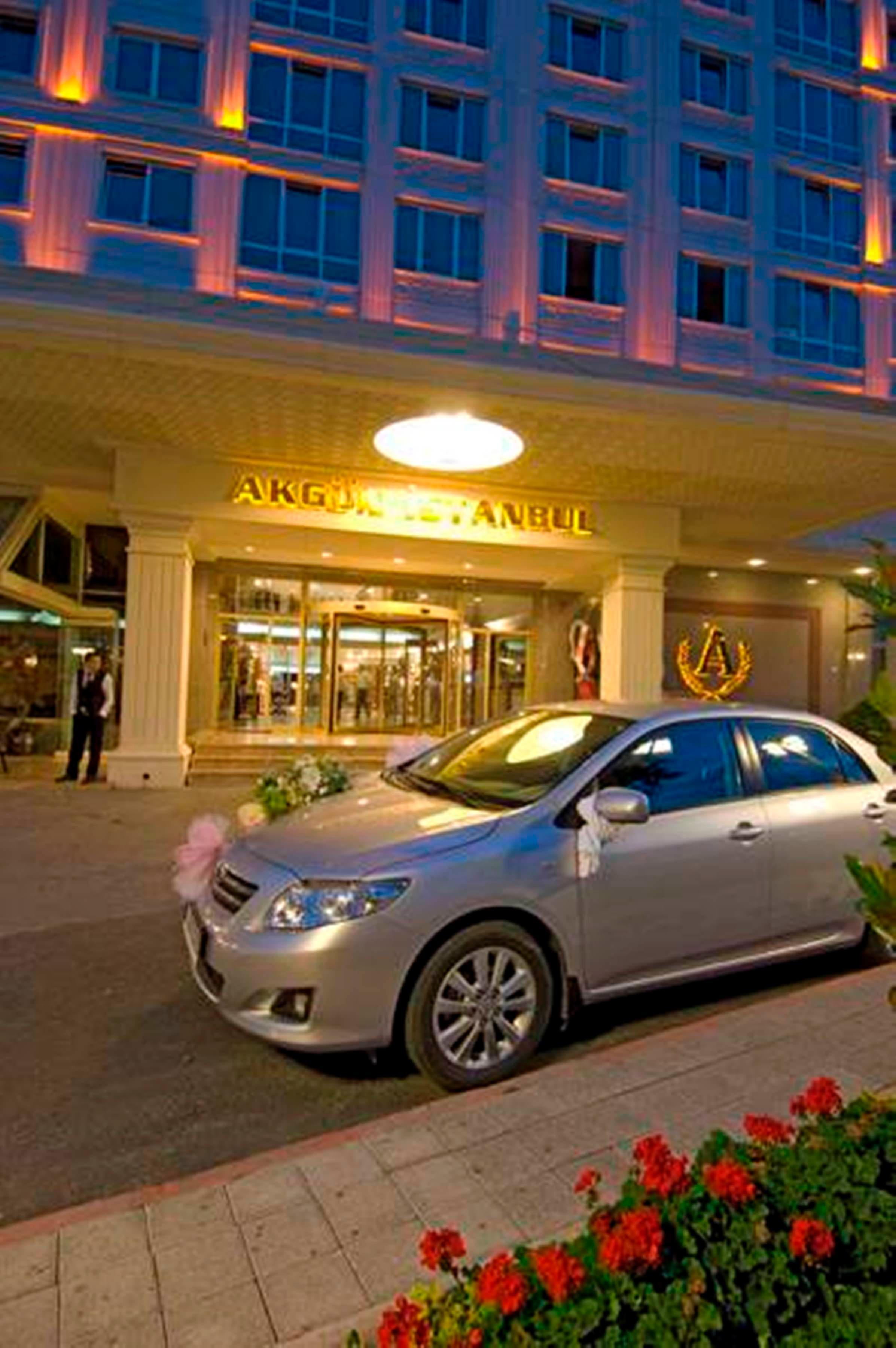 Akgun Istanbul Hotel Exterior foto The photo shows the entrance of a hotel named "Akgün Istanbul." In front of the hotel, there is a silver car adorned with decorative flowers, indicating it might be for a special occasion, such as a wedding. The hotel entrance features large glass do