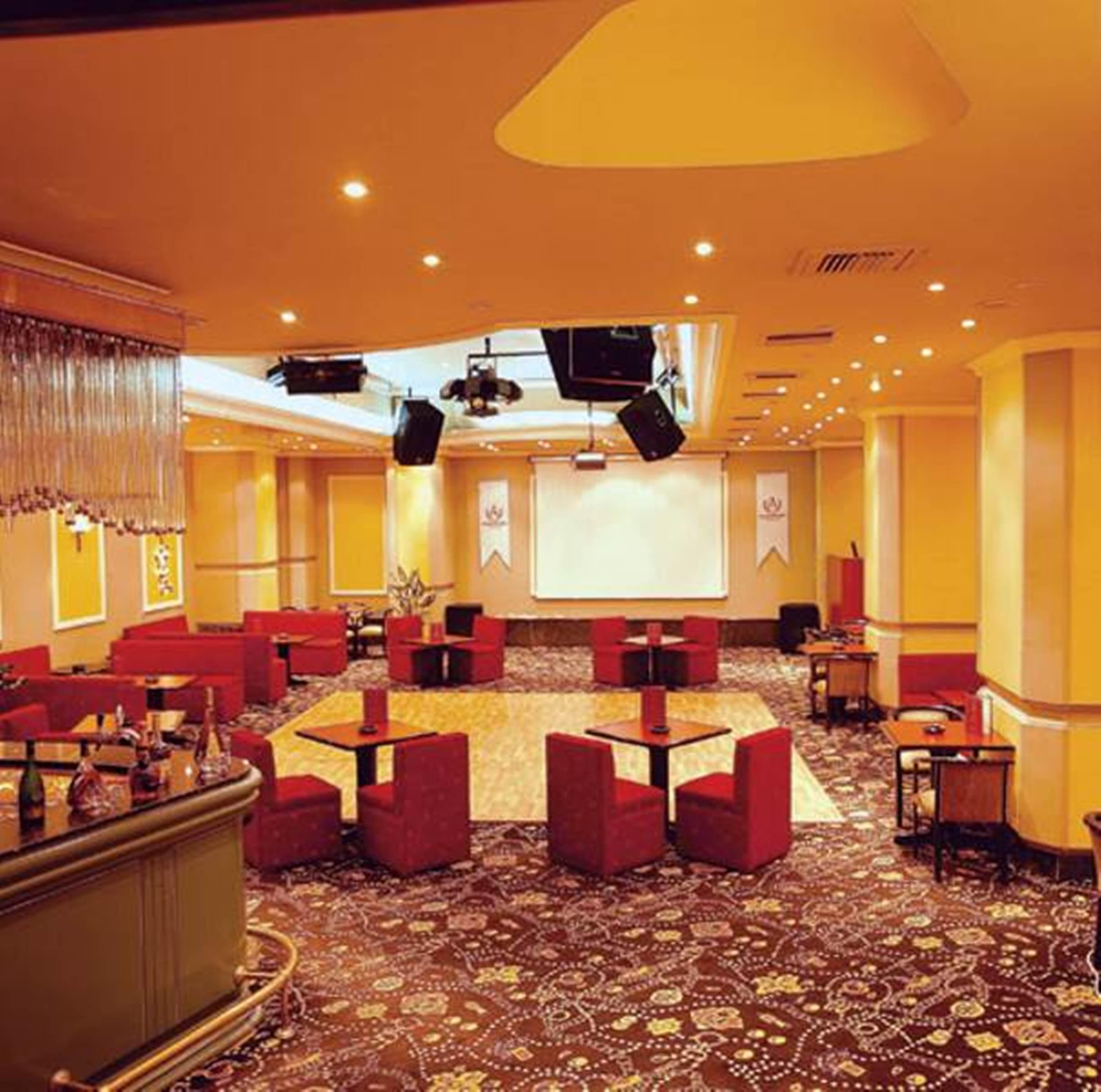 Akgun Istanbul Hotel Exterior foto The photo shows an interior of a venue, likely a lounge or event space. The room features a spacious layout with a wooden dance floor in the center. Surrounding the dance area are several small tables and chairs arranged in clusters. The seating is r