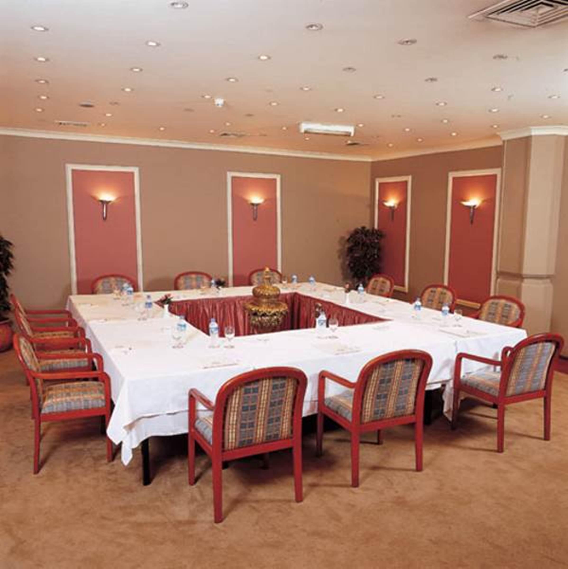Akgun Istanbul Hotel Exterior foto The image shows a conference room setup with a large, rectangular table in the center, surrounded by several chairs. The table is covered with white tablecloths and has water bottles placed on it. The walls are painted in a light brown color with dec