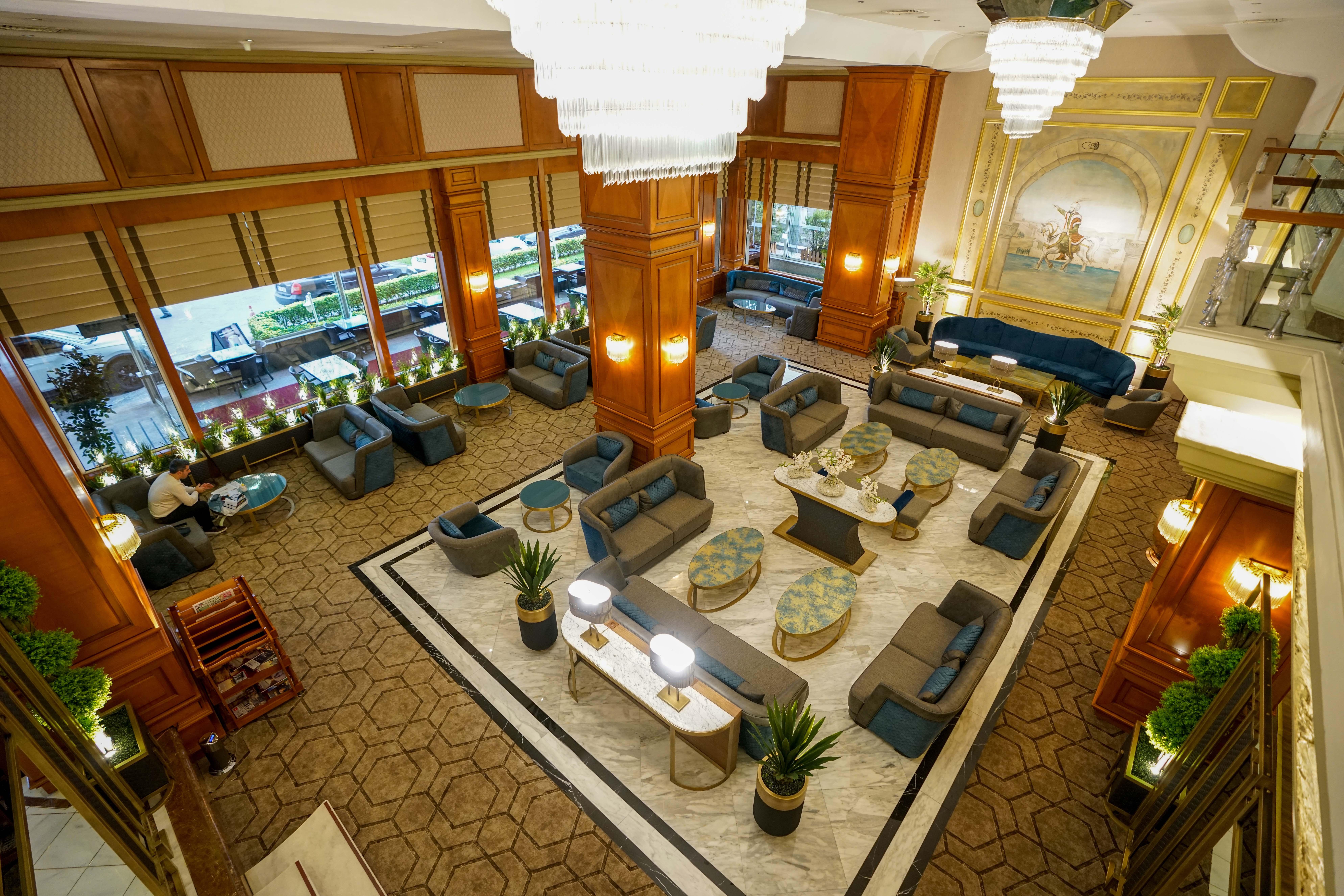 Akgun Istanbul Hotel Exterior foto The photo shows a spacious and elegantly designed hotel lobby. The area features a combination of comfortable seating arrangements, including sofas and armchairs, arranged around coffee tables. The decor highlights warm wooden accents and stylish lig