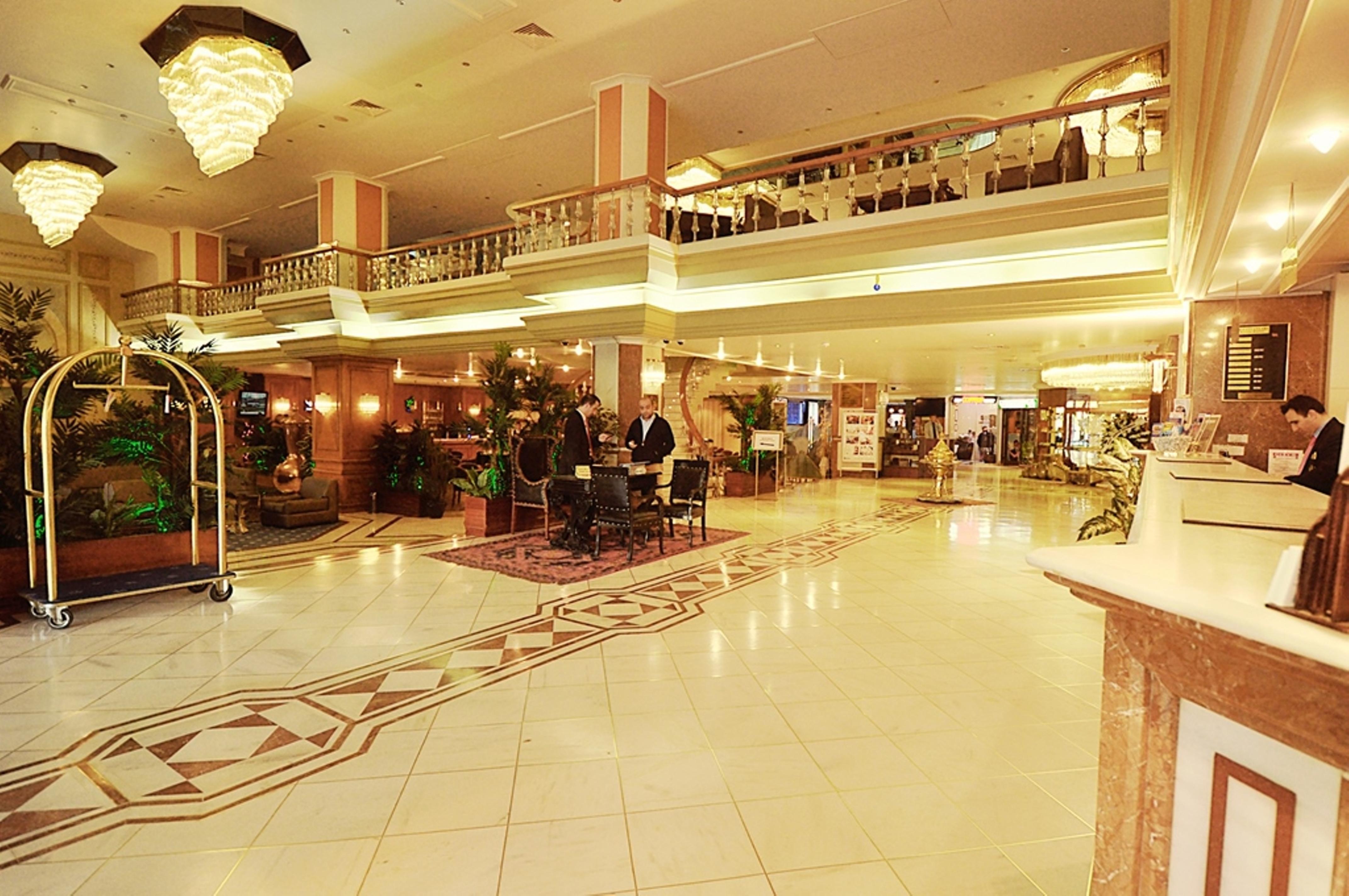 Akgun Istanbul Hotel Exterior foto The photo depicts a luxurious hotel lobby. The interior features elegant marble flooring with a geometric pattern, high ceilings, and well-lit spaces. To the left, there is a reception desk, and the area is adorned with lush indoor plants, enhancing 