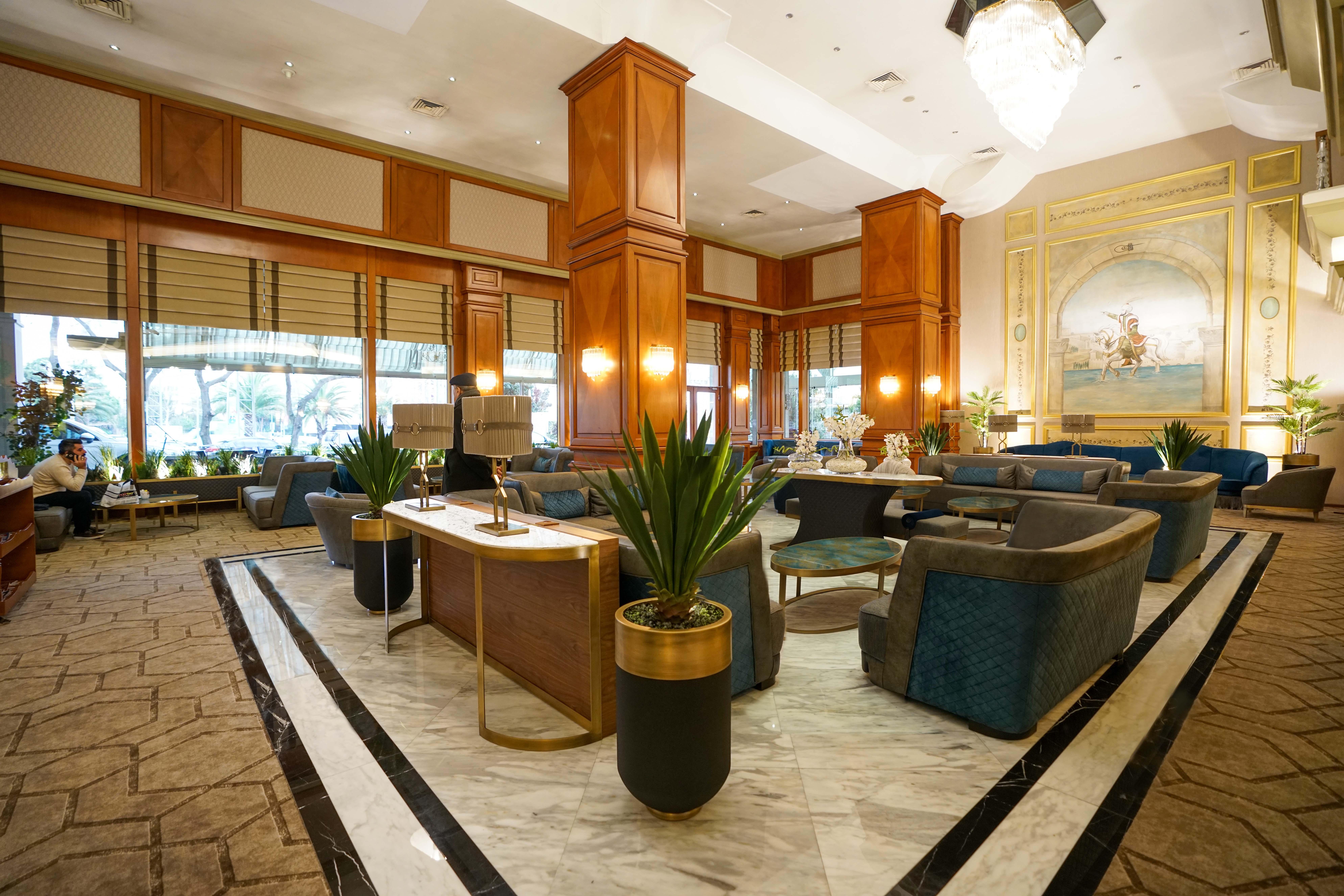 Akgun Istanbul Hotel Exterior foto The photo shows a stylish hotel lobby with a welcoming atmosphere. The space features elegant wooden paneling and large windows, allowing natural light to illuminate the area. Comfortable seating arrangements are set around circular tables, with plus