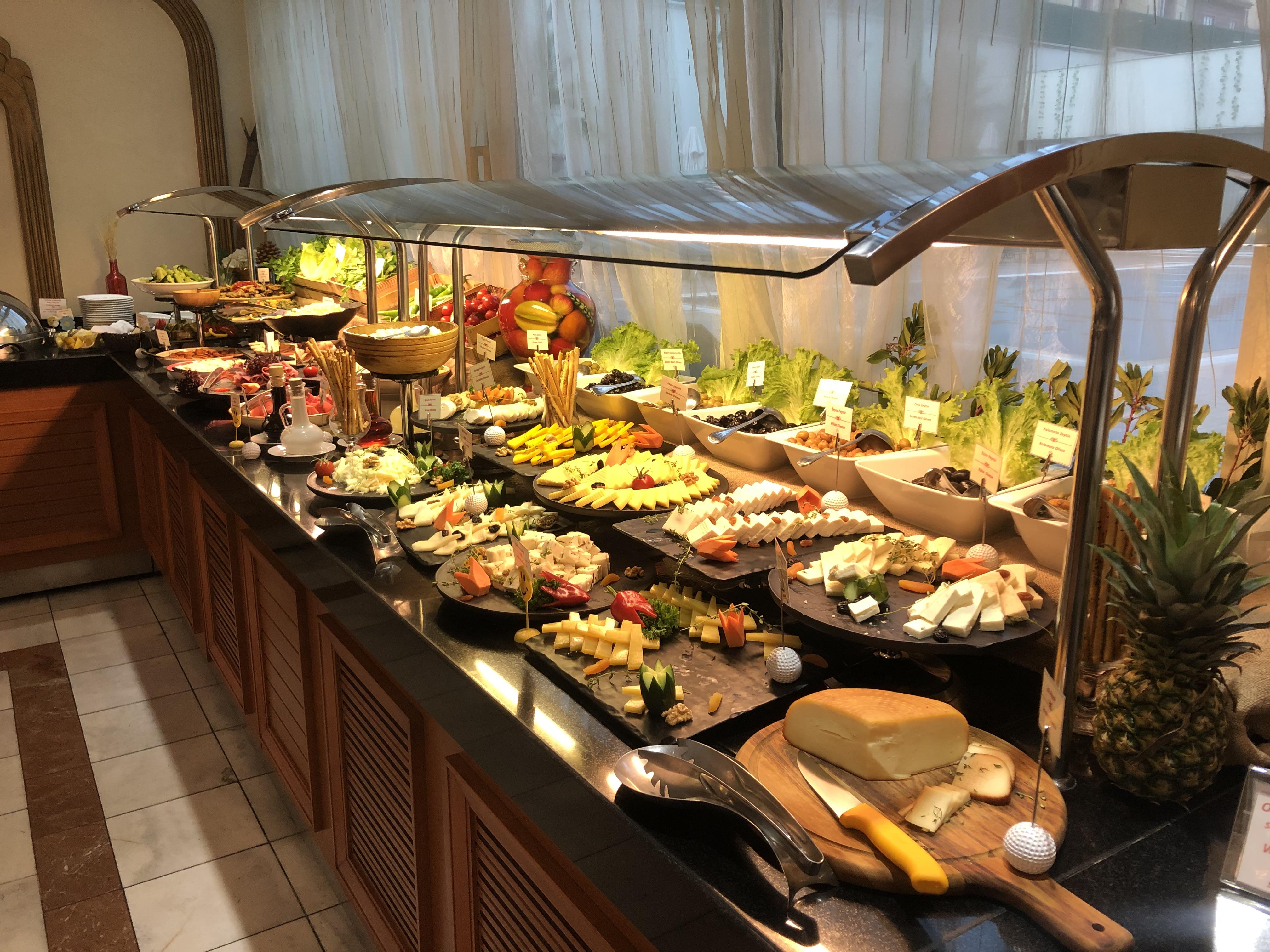 Akgun Istanbul Hotel Exterior foto The photo shows an extensive buffet spread featuring a variety of food items. There are multiple trays filled with colorful and diverse dishes, including fresh fruits, salads, and various appetizers. The arrangement is visually appealing, with items 