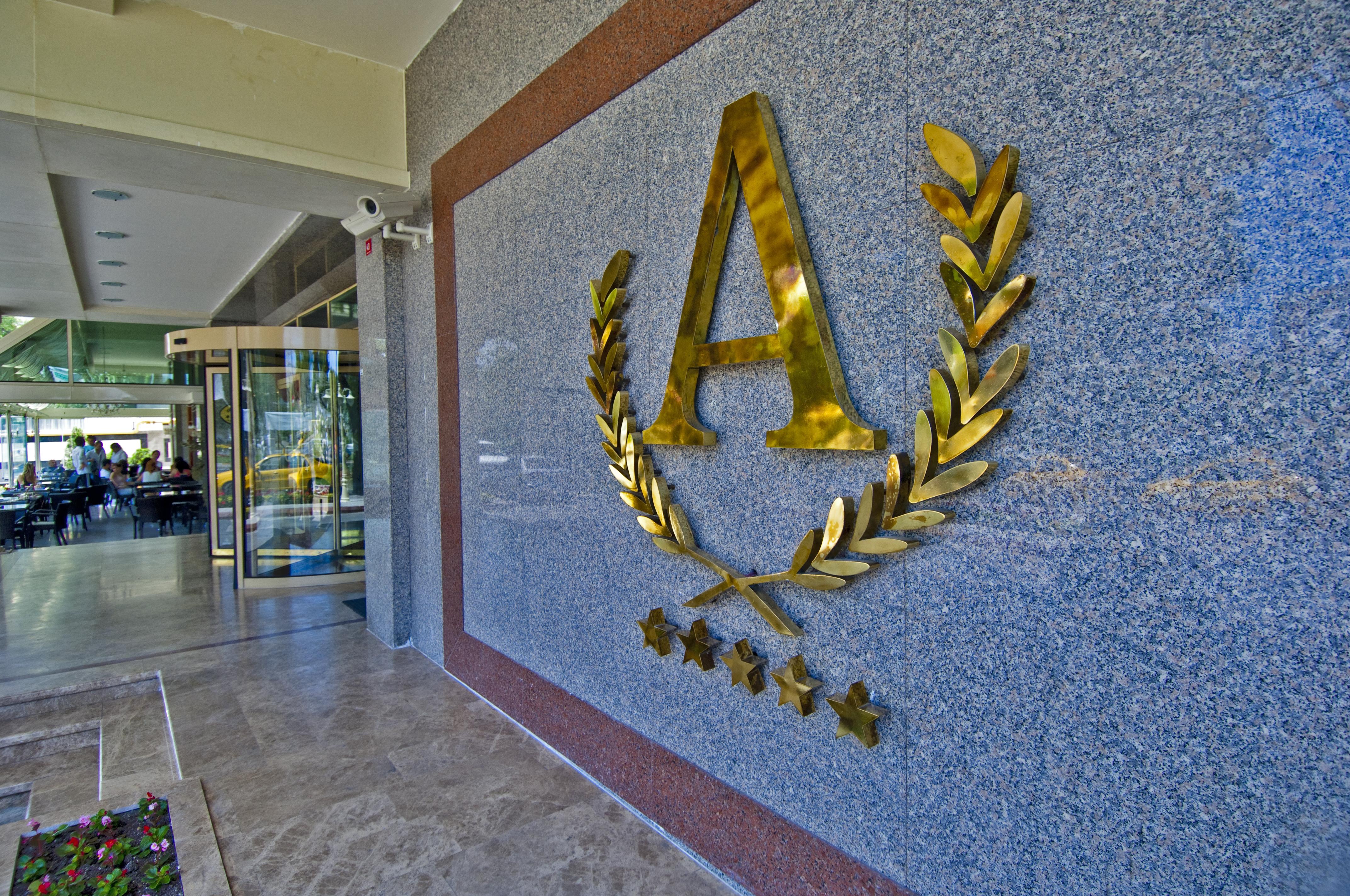 Akgun Istanbul Hotel Exterior foto The photo shows a decorative wall feature made of granite or a similar material. Prominently displayed is a large, shiny gold letter "A" that is surrounded by a laurel wreath, symbolizing achievement or excellence. Below the letter and wreath, there 