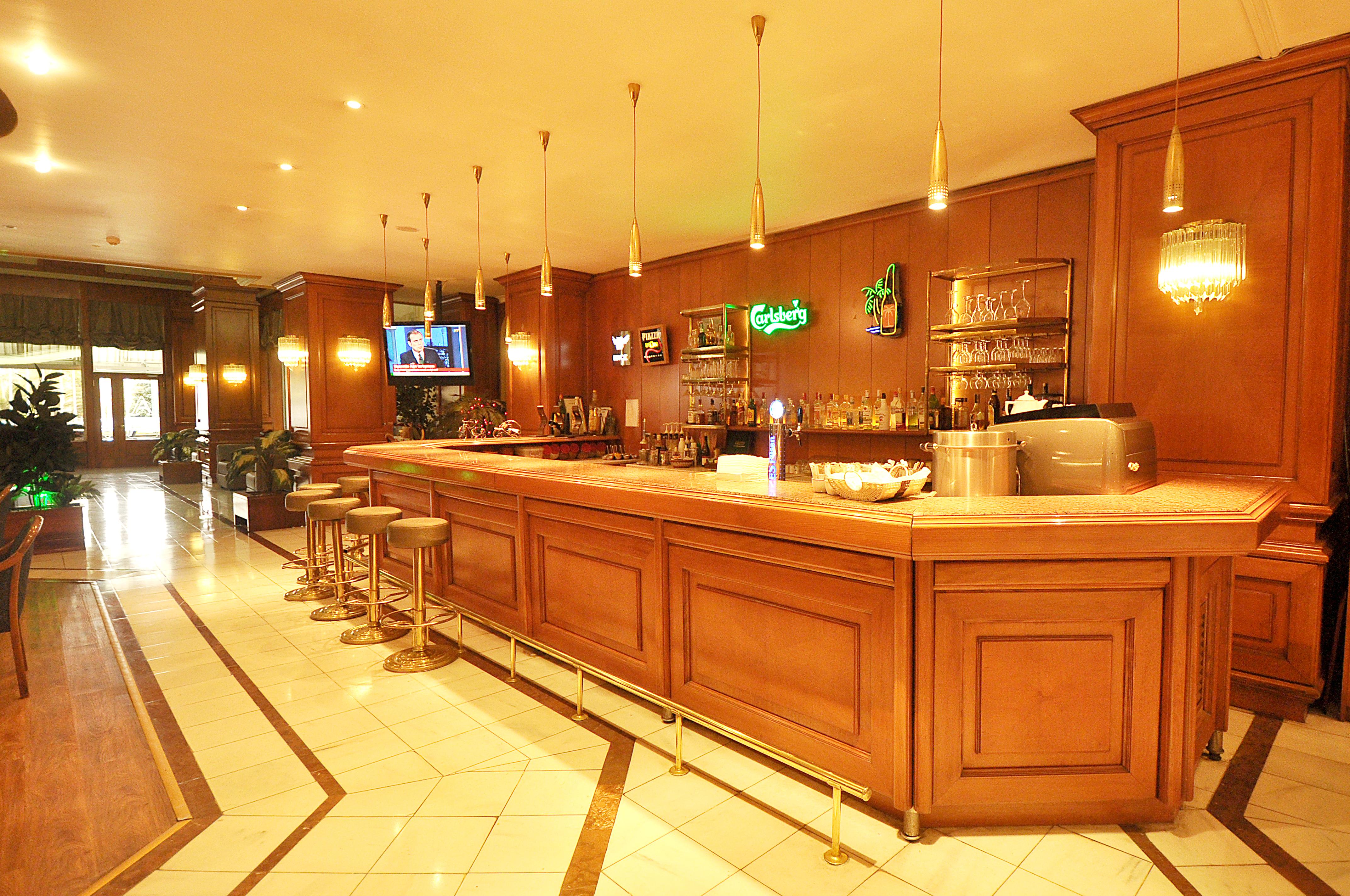 Akgun Istanbul Hotel Exterior foto The photo shows a bar area with a polished wooden bar counter, illuminated by pendant lights hanging from the ceiling. Behind the bar, there are shelves displaying various bottles and glasses. A television is mounted on the wall, and a few bar stools