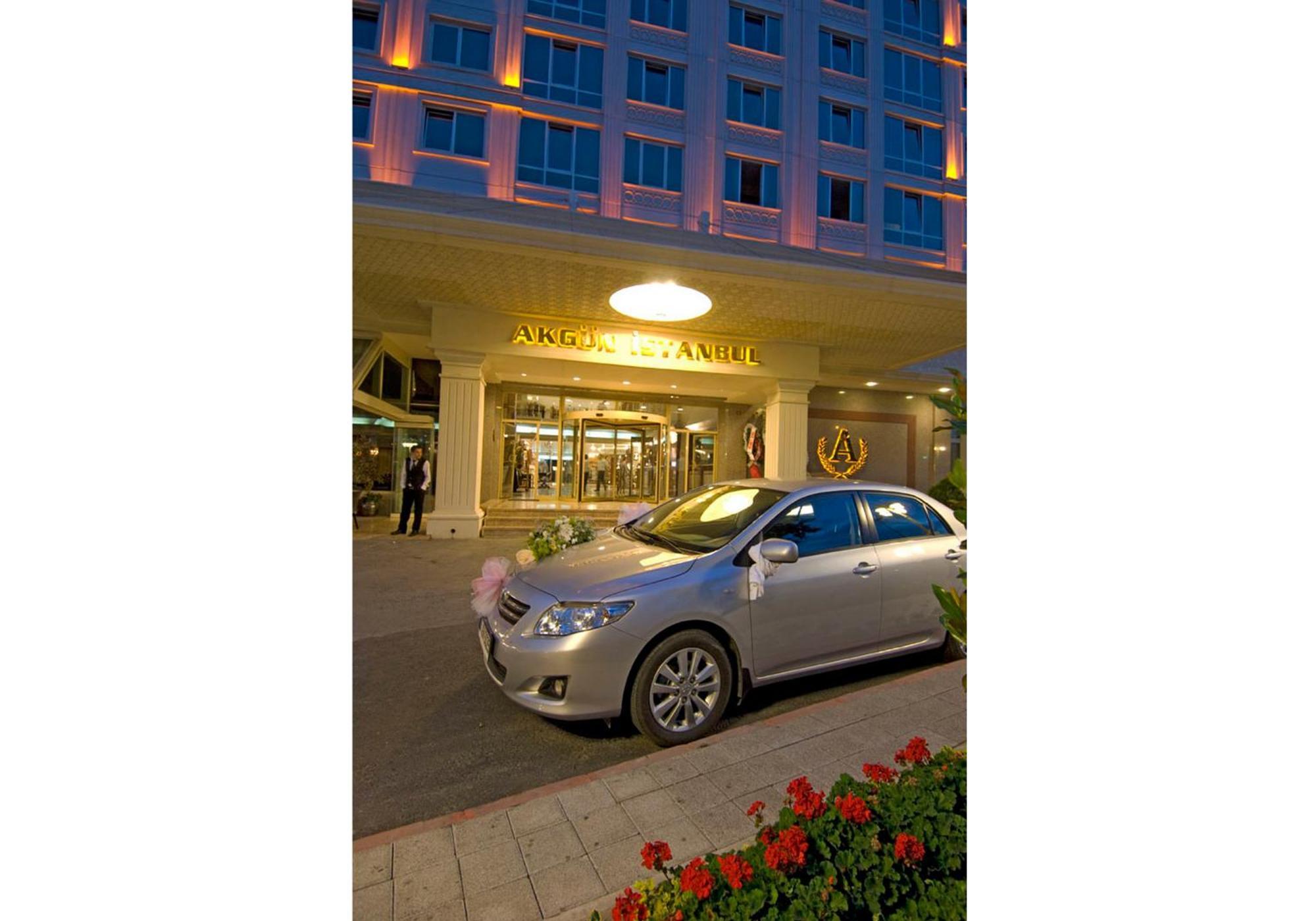 Akgun Istanbul Hotel Exterior foto The photo shows a modern hotel entrance with a prominent sign, likely indicating the hotel's name. In front of the hotel, there is a silver car parked, adorned with decorative elements, possibly for a special occasion such as a wedding. The hotel's f