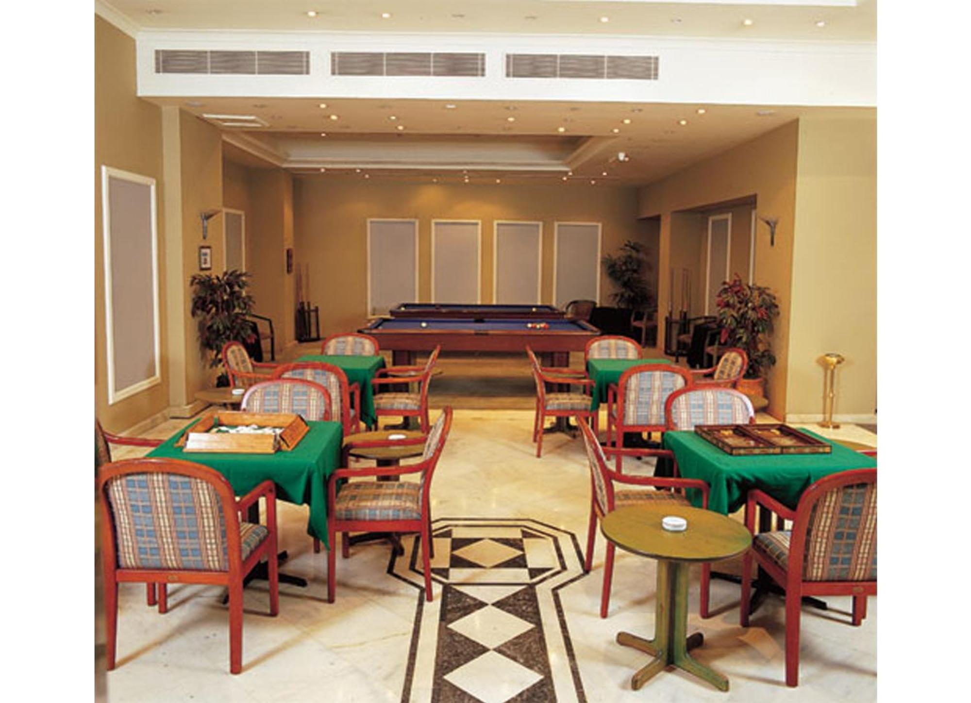Akgun Istanbul Hotel Exterior foto The photo displays an interior shot of a lounge or recreational area. The space includes several tables covered with green tablecloths, positioned in the foreground with chairs around them. In the background, there is a billiards table, suggesting a 