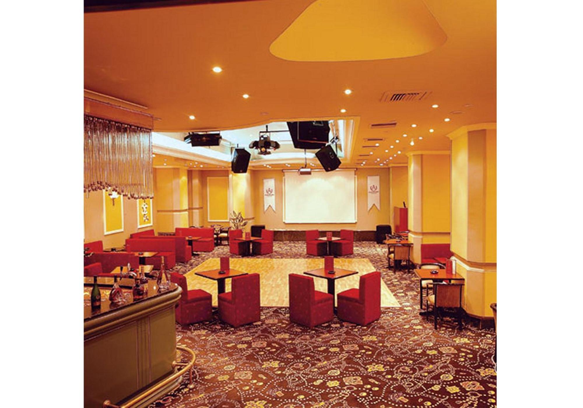 Akgun Istanbul Hotel Exterior foto The photo shows an interior space that appears to be a lounge or event room. The walls are painted a warm yellow, and the lighting is soft, with multiple ceiling lights illuminating the area. There are several red chairs arranged around dark tables, 